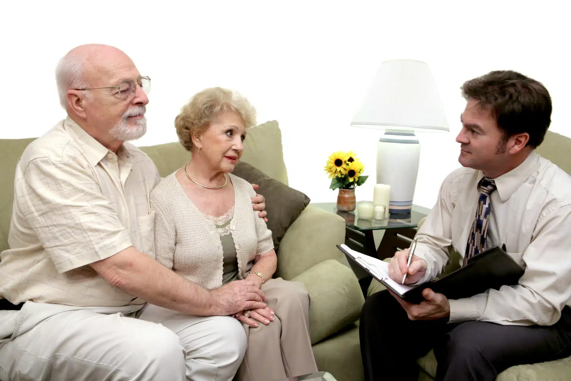 Man taking notes in chair while facing couple seated on sofa