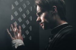 Stressed young priest peers through confessional grille