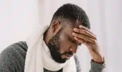 Stressed man holds his forehead with one hand