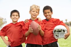Three boys with football and helmet