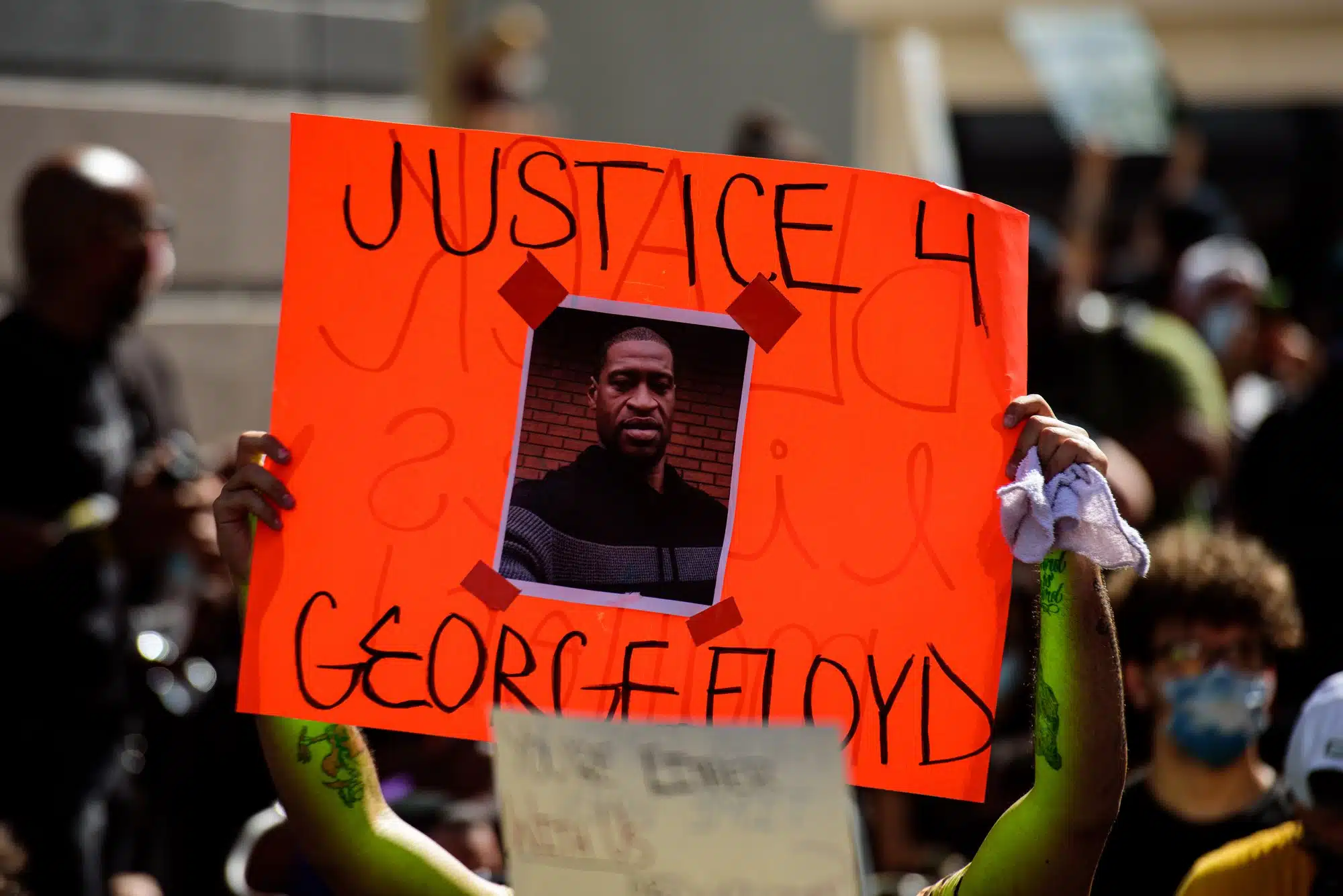 Person at Black Lives Matter protest holding Justice for Floyd sign