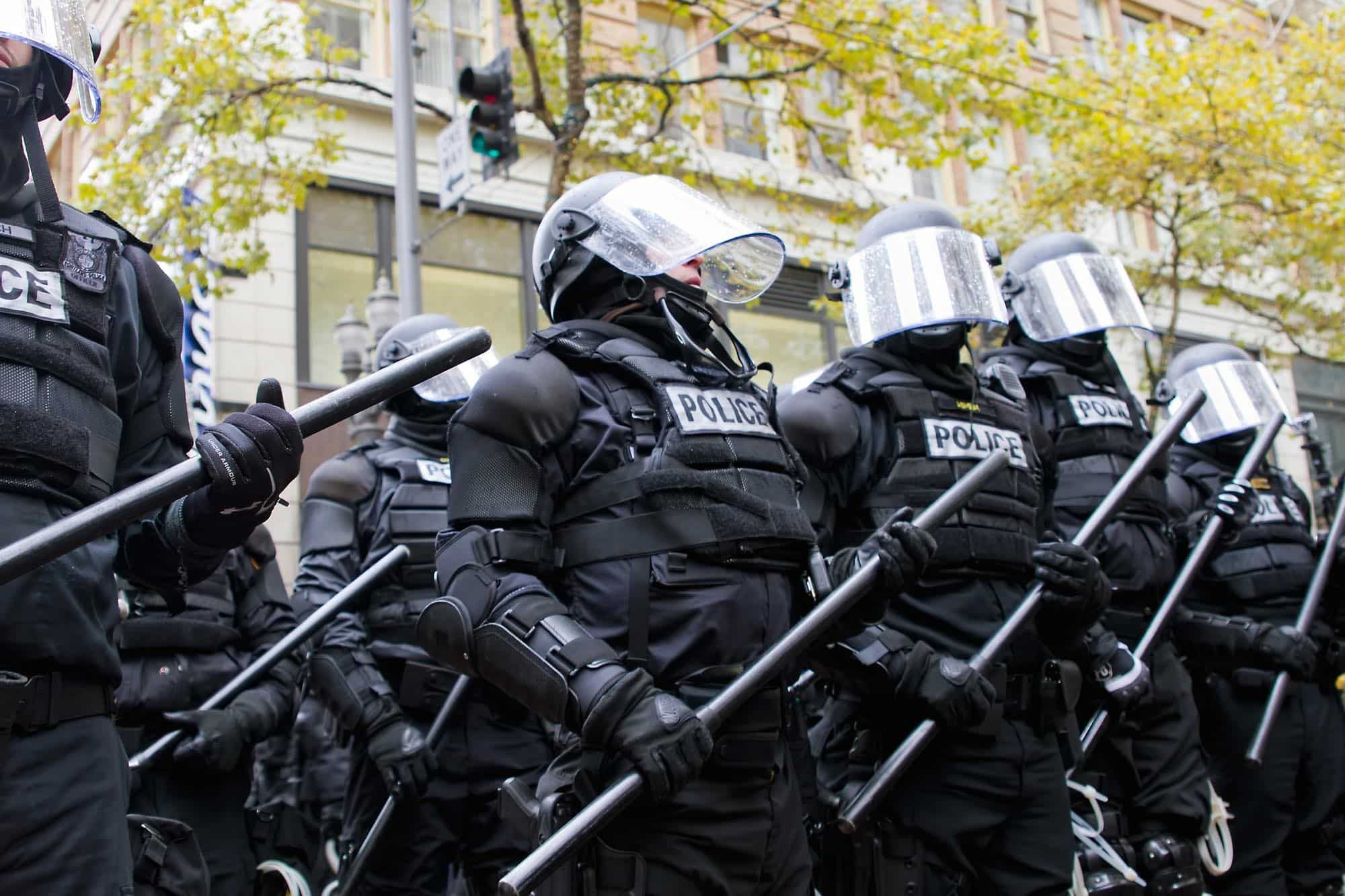 police wearing riot gear engaging in police brutality