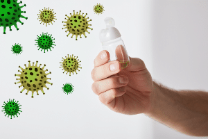Illustration of germs and photo of hand holding open sanitizer bottle