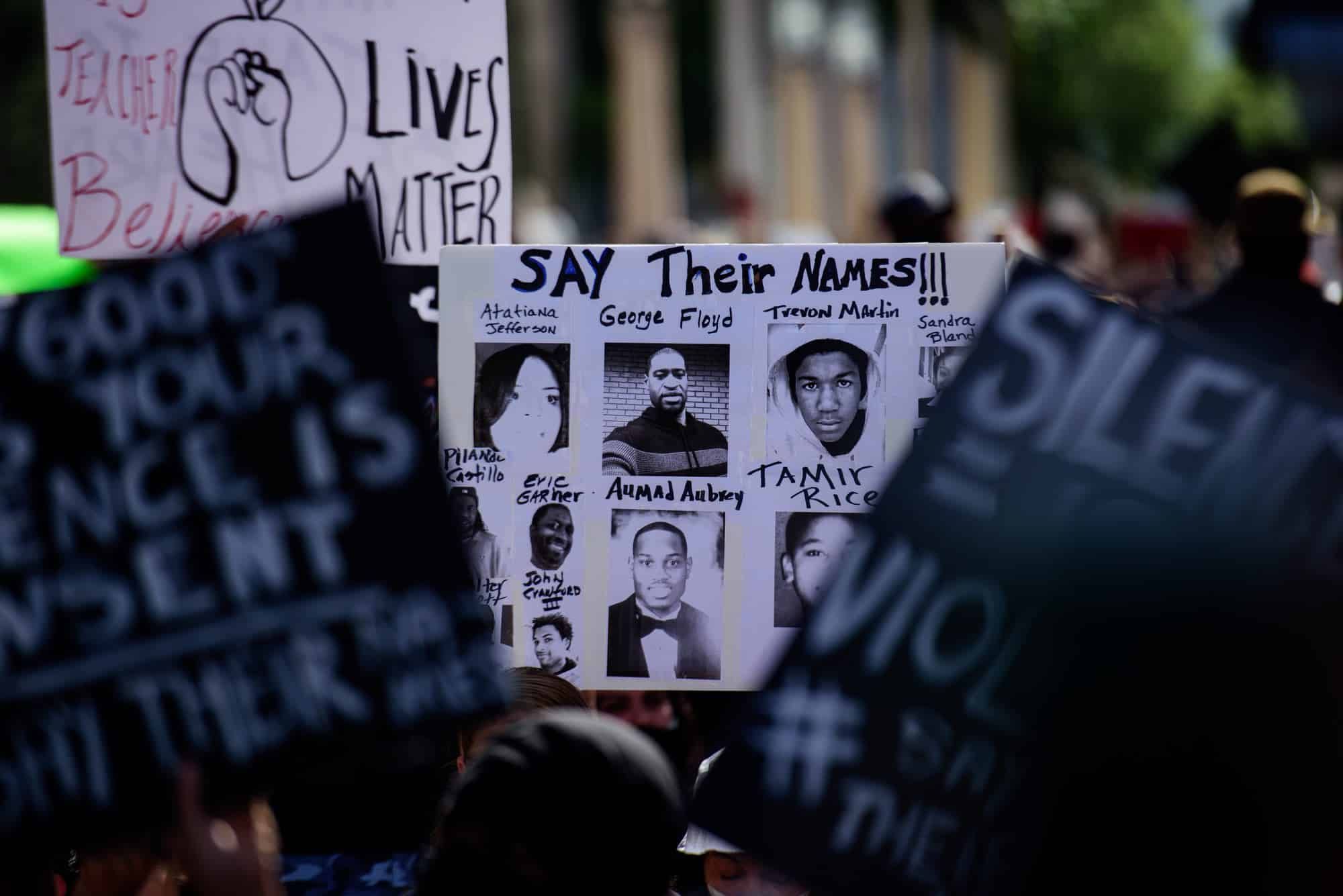 Dallas police during protest, person holding say their names sign