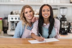 Two waitresses behind the counter at a restaurant.