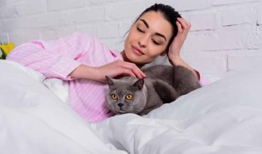 A woman pets a cat.