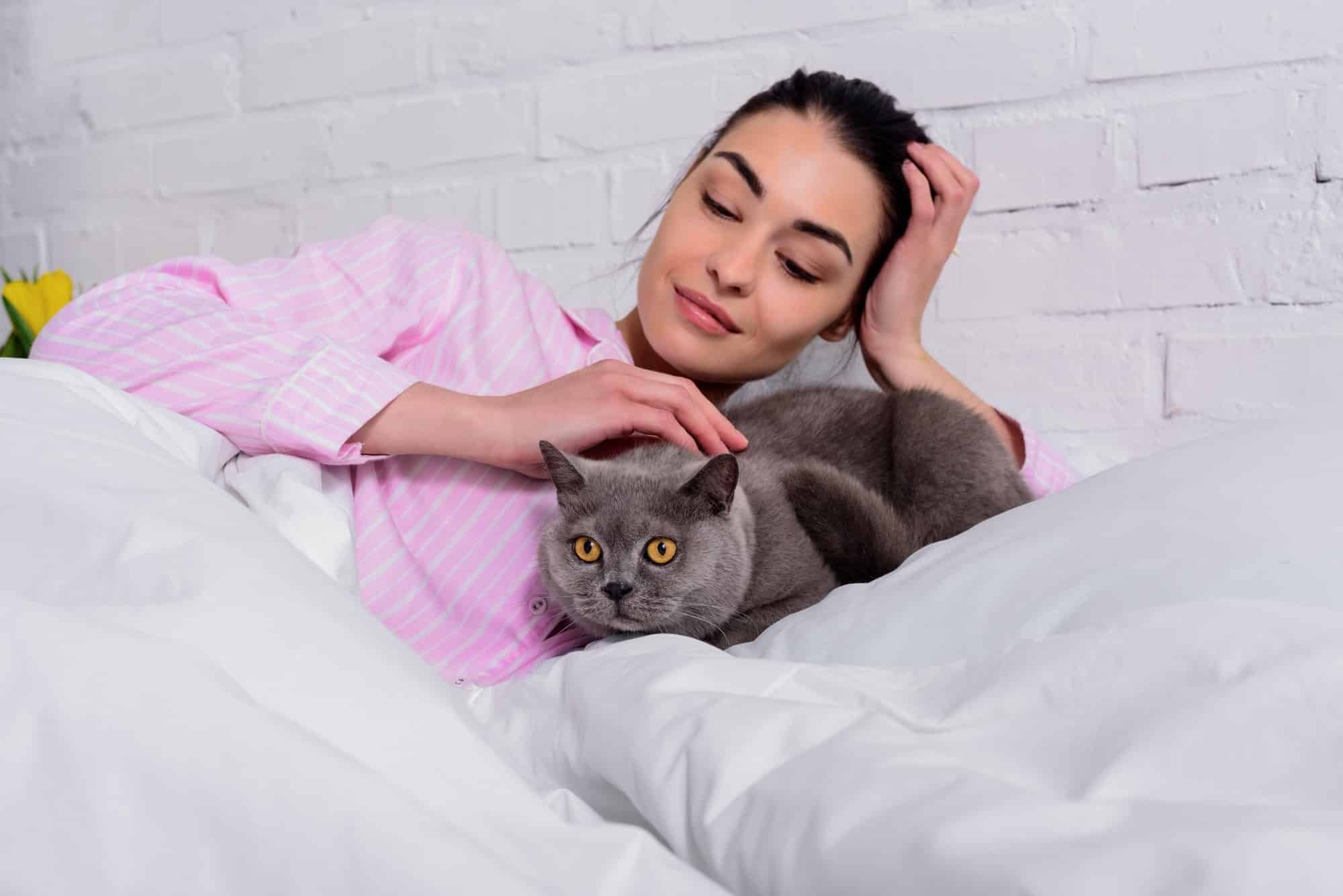 A woman pets a cat.
