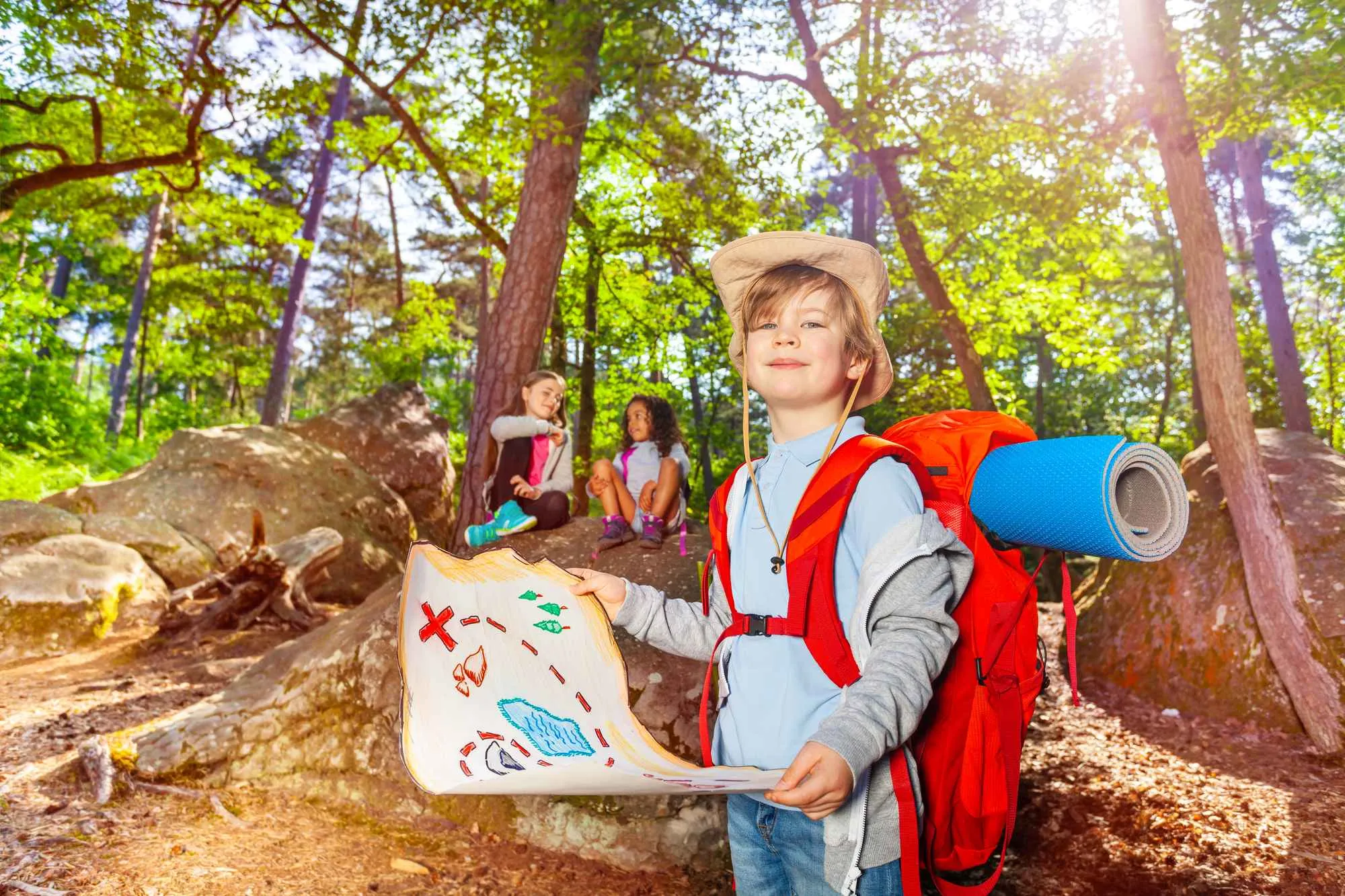 Boy holds an open map in the woods