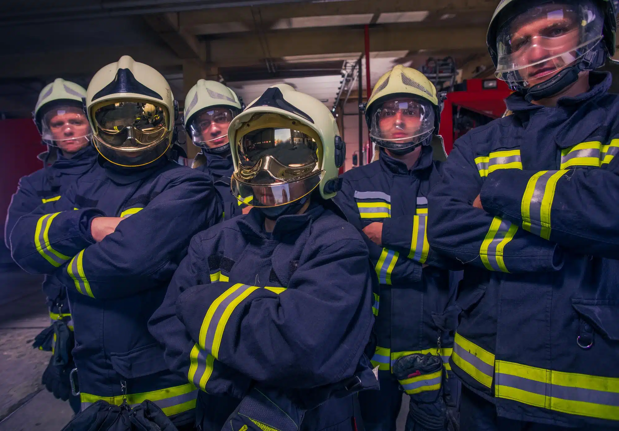 Group of firefighters in protective gear stand in front of firetruck