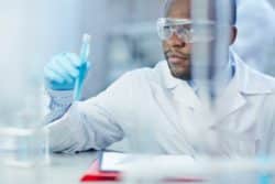 Male chemist holds vial of blue liquid