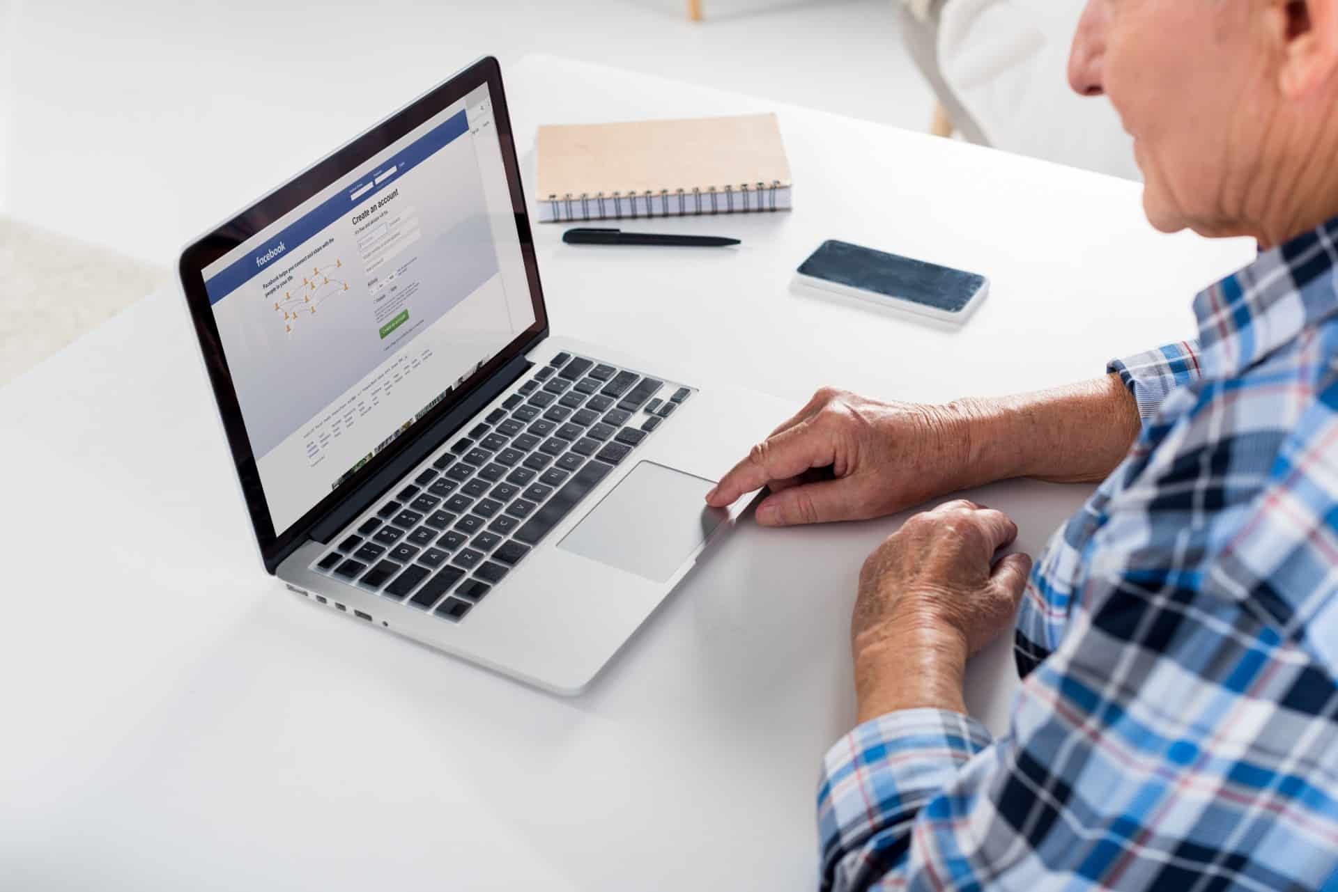 Older man uses Facebook on a laptop