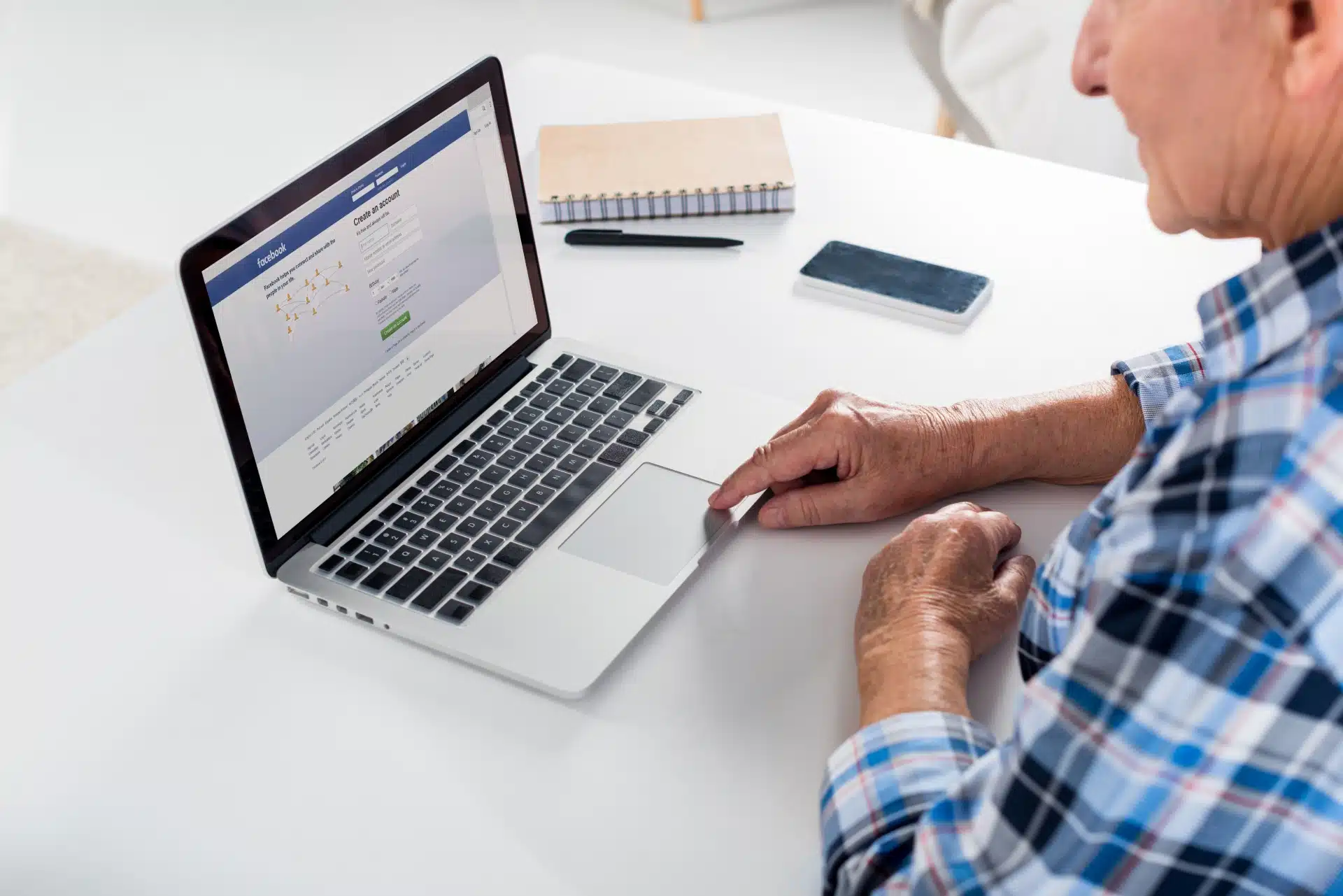 Older man uses Facebook on a laptop
