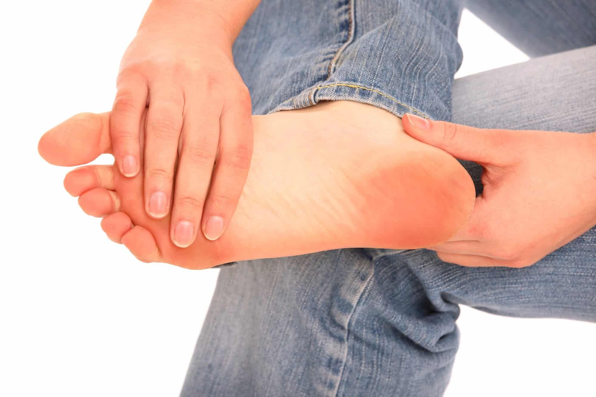 Person seated, holding their foot and looking for issues