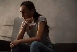 Crying woman sits on couch and holds a napkin