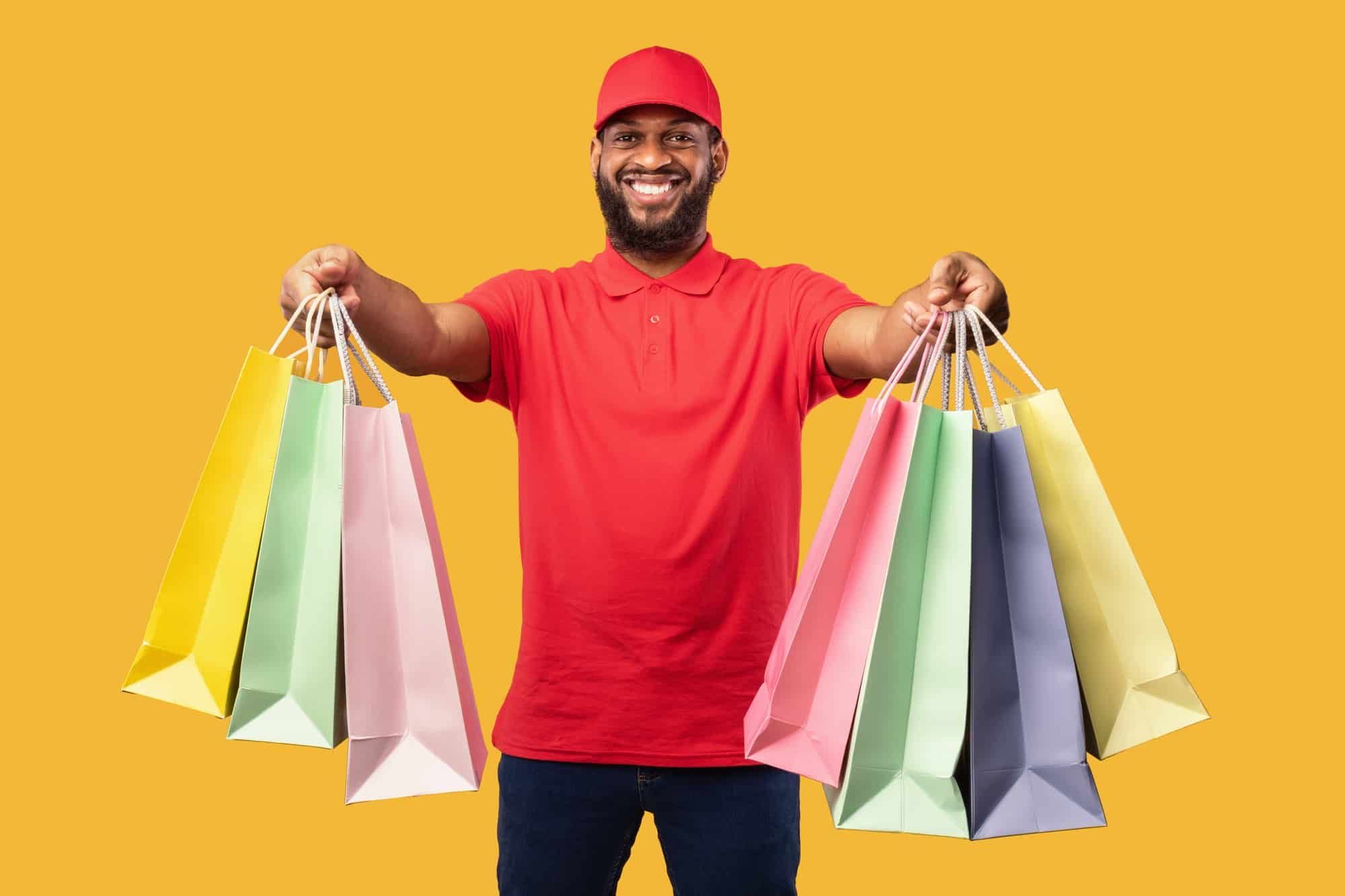 Happy man holds out shopping bags for delivery