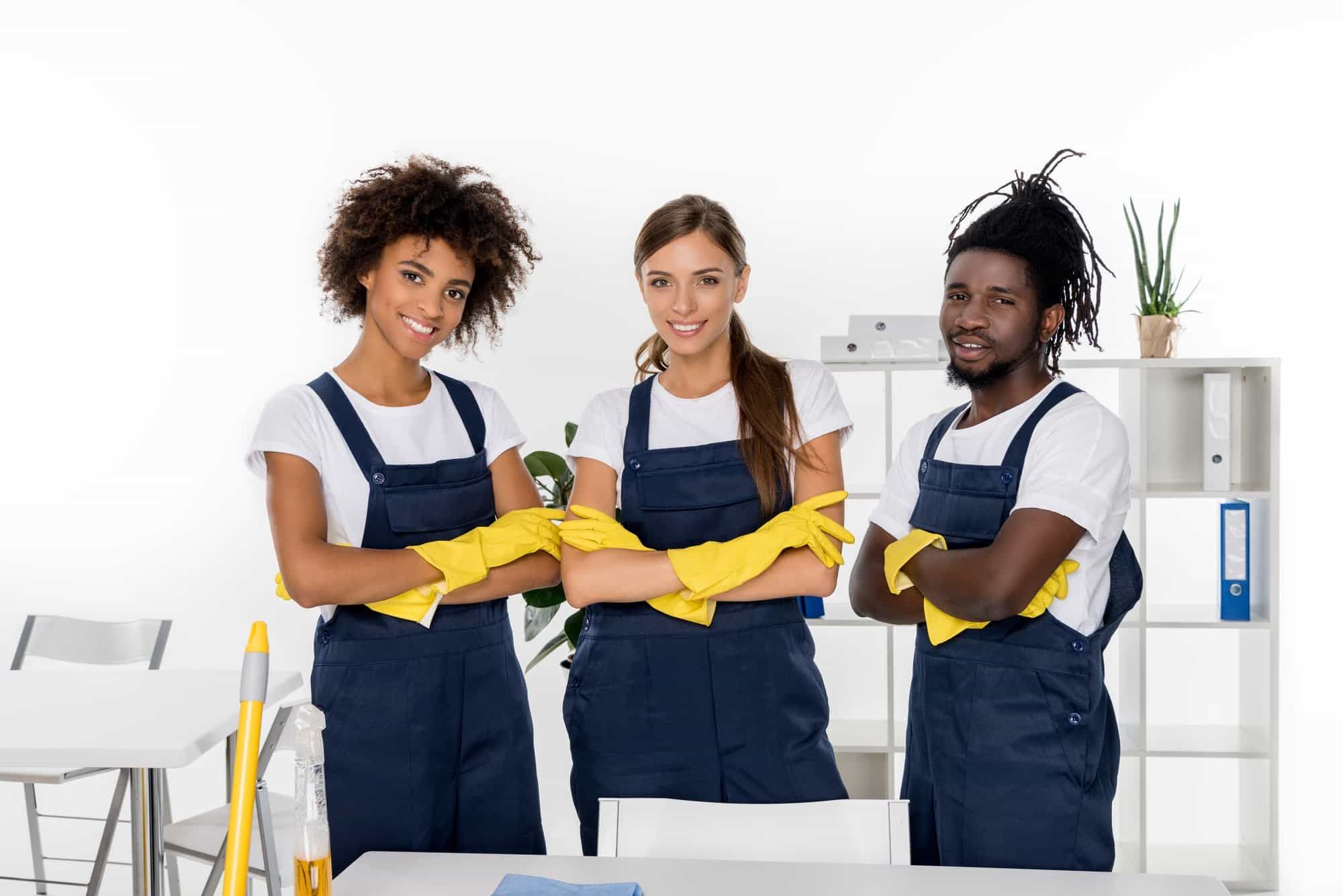 Two female and one male professional cleaners in overalls and gloves