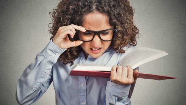 Woman adjusts glasses while trying to read book