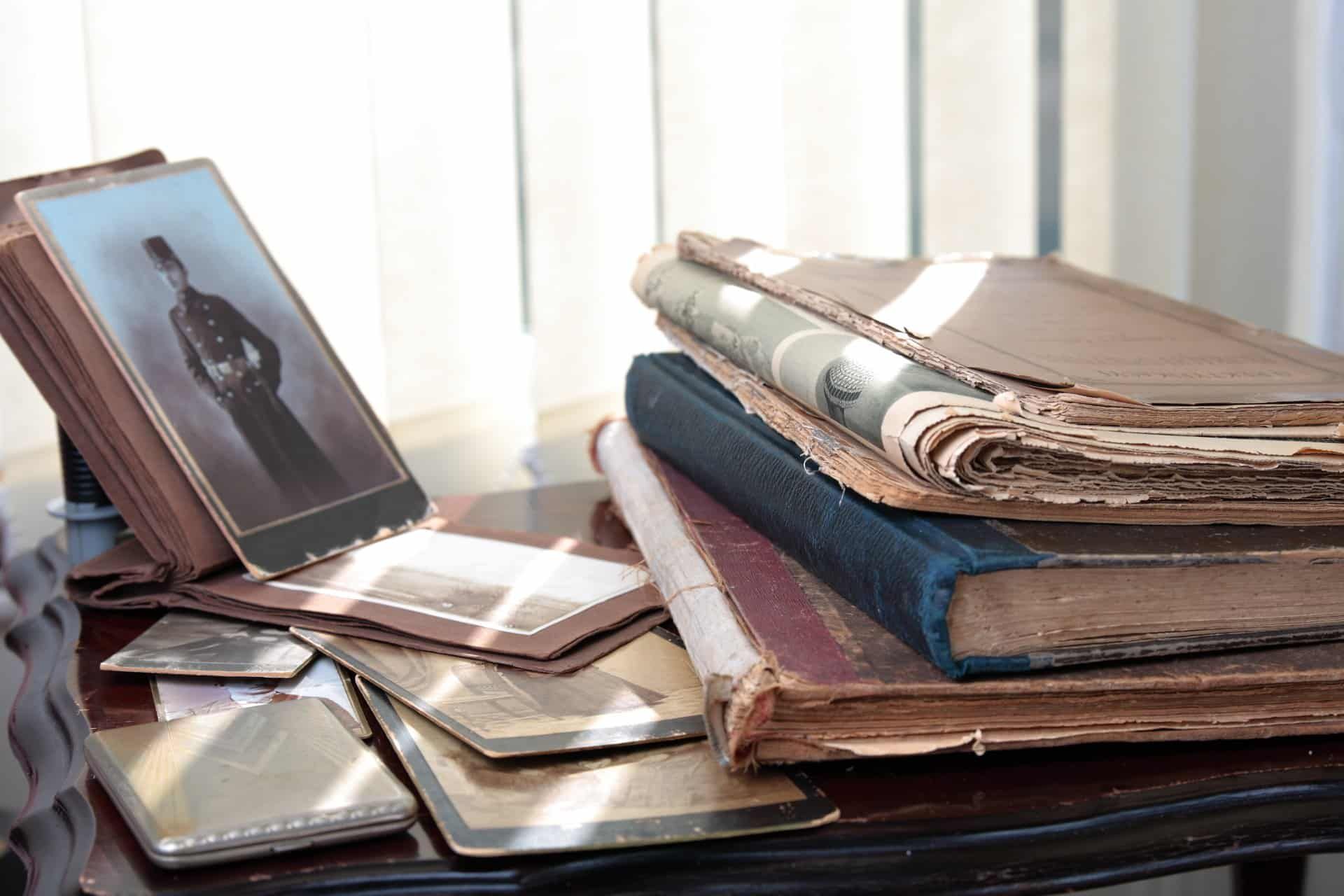 Historic photos and books sit on a desk in the sunlight - Ancestry.com