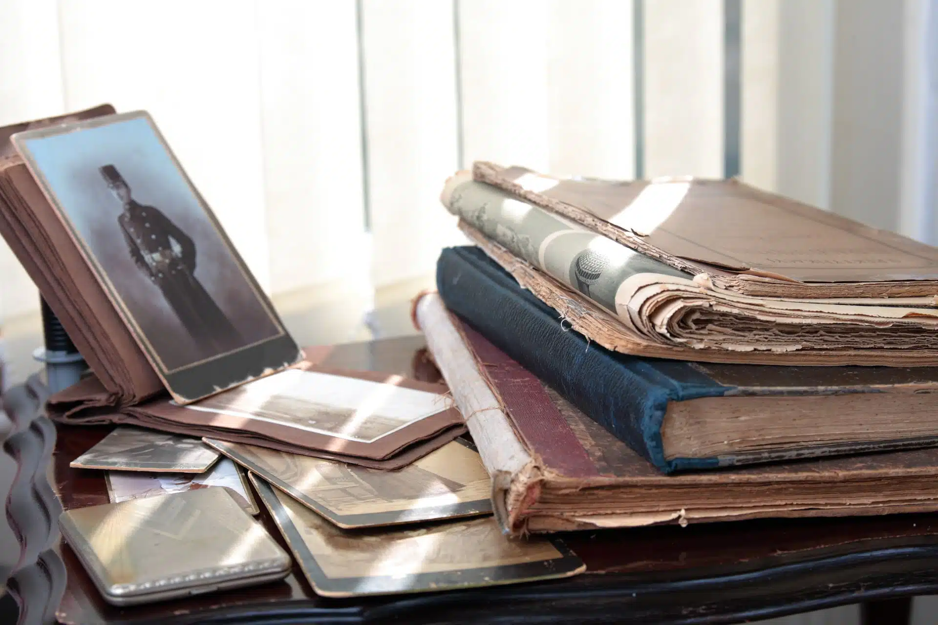 Historic photos and books sit on a desk in the sunlight - Ancestry.com