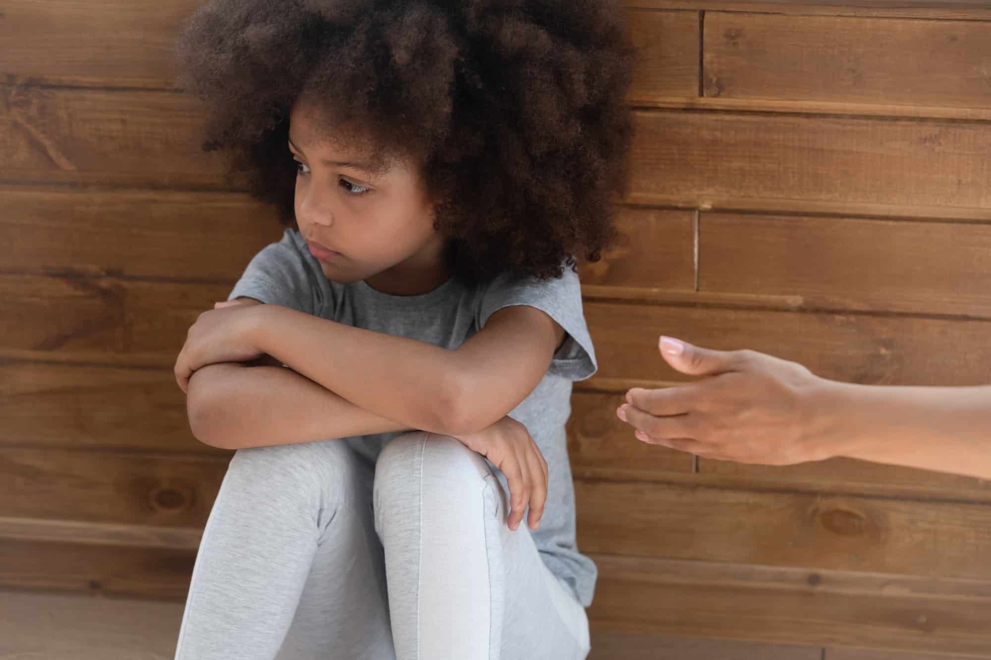 Sad young girl ignores mom's hand reaching out