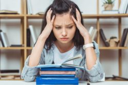 Upset female student sits with open book but has trouble concentrating