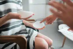 Woman touches texture of breast implant sample while talking to surgeon