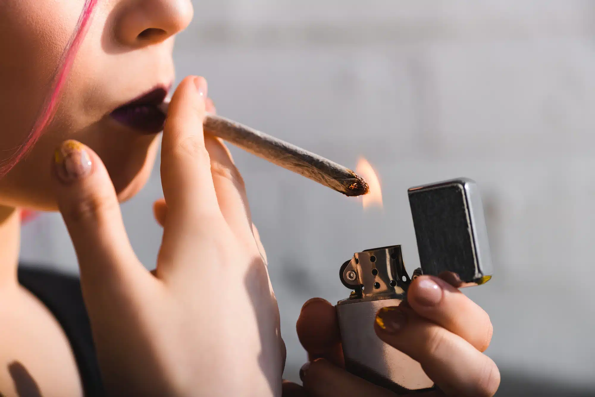 Close up of young woman lighting marijuana blunt