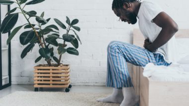 Man has abdominal pain sitting on edge of bed