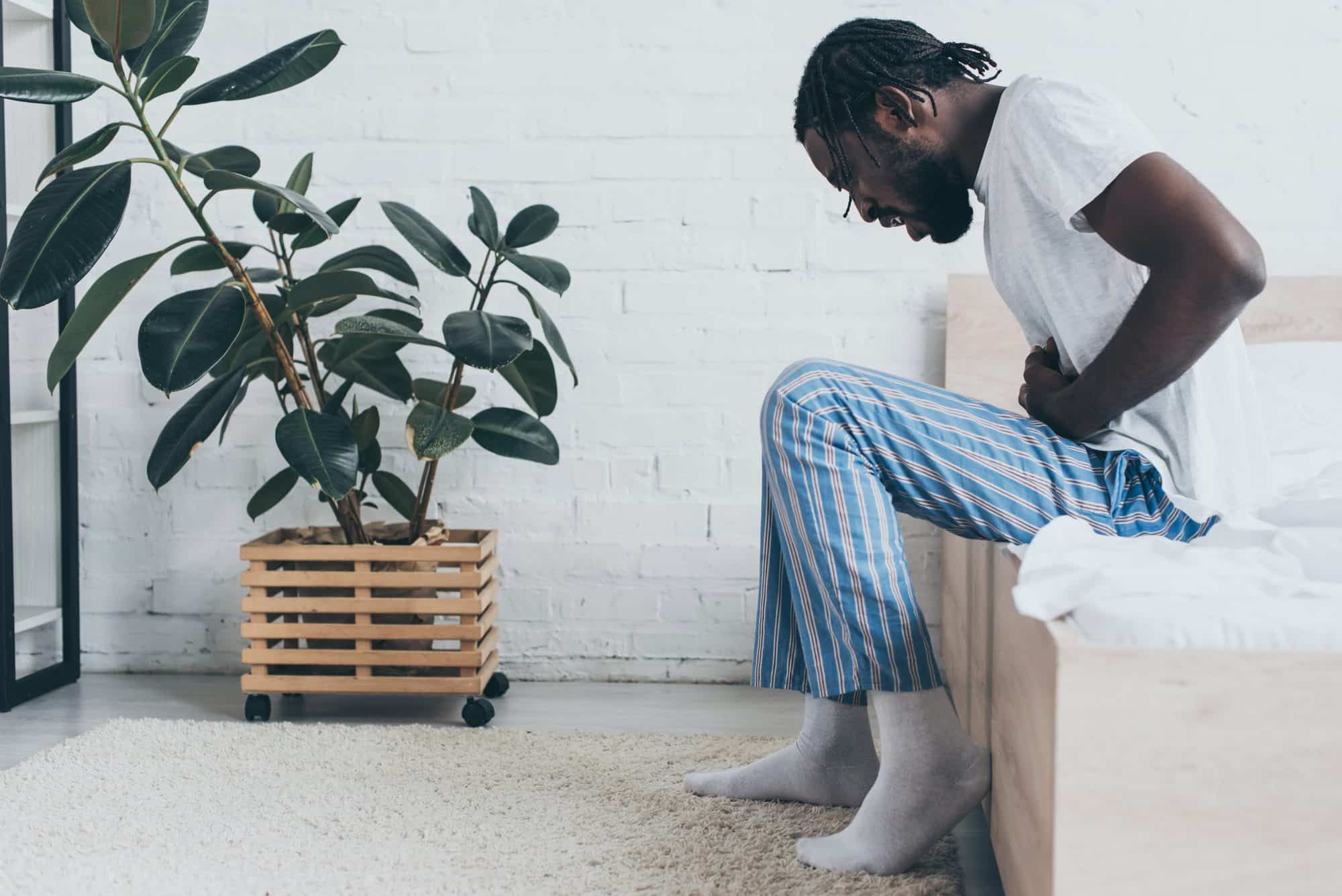 Man has abdominal pain sitting on edge of bed