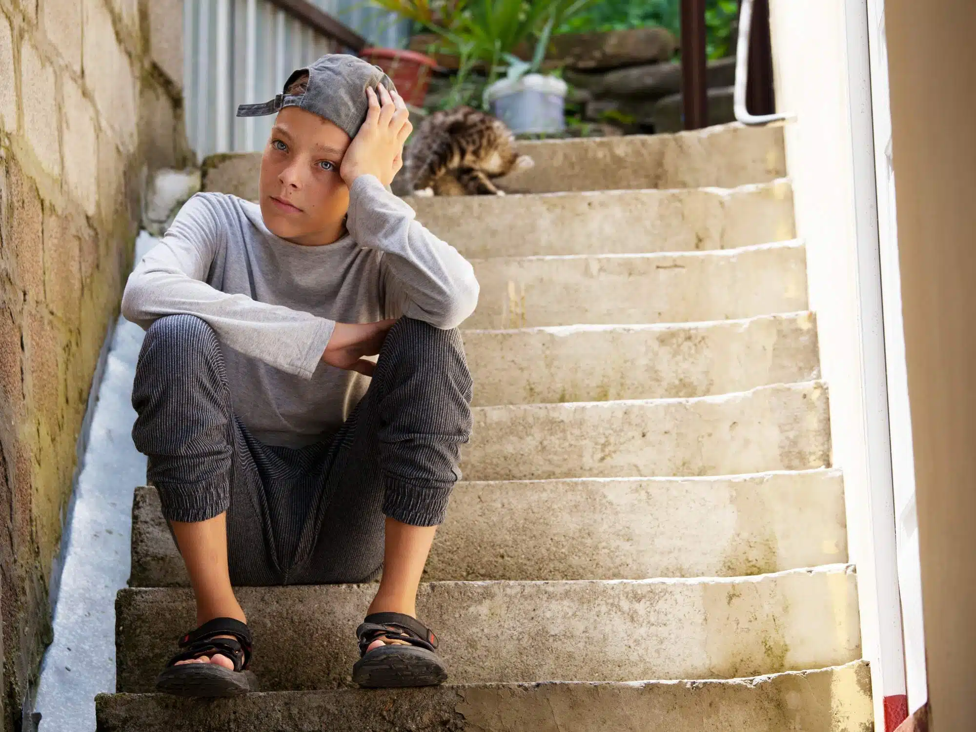 Sad teen boy sits on stairs outside