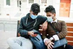 Two masked students look at cell phone