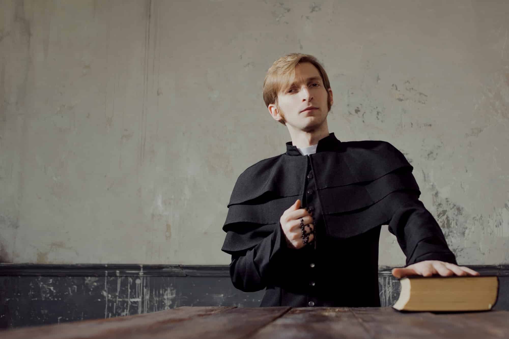 Young priest with hand on Bible, other hand holds rosary