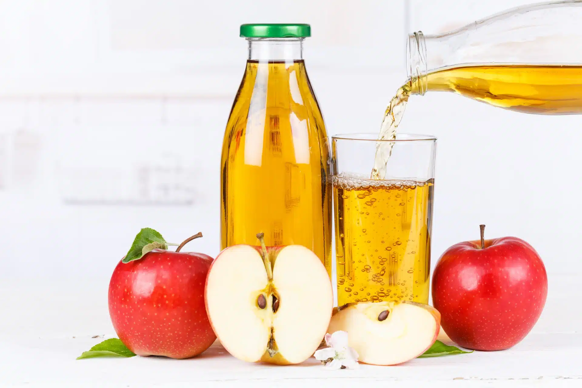 Sliced and whole apples sit next to a bottle of apple juice as someone pours juice into a glass - Mott's 100% Apple Juice