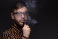 Man in glasses and beard vapes