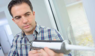Man uses sealant gun on glass - dap clear sealant