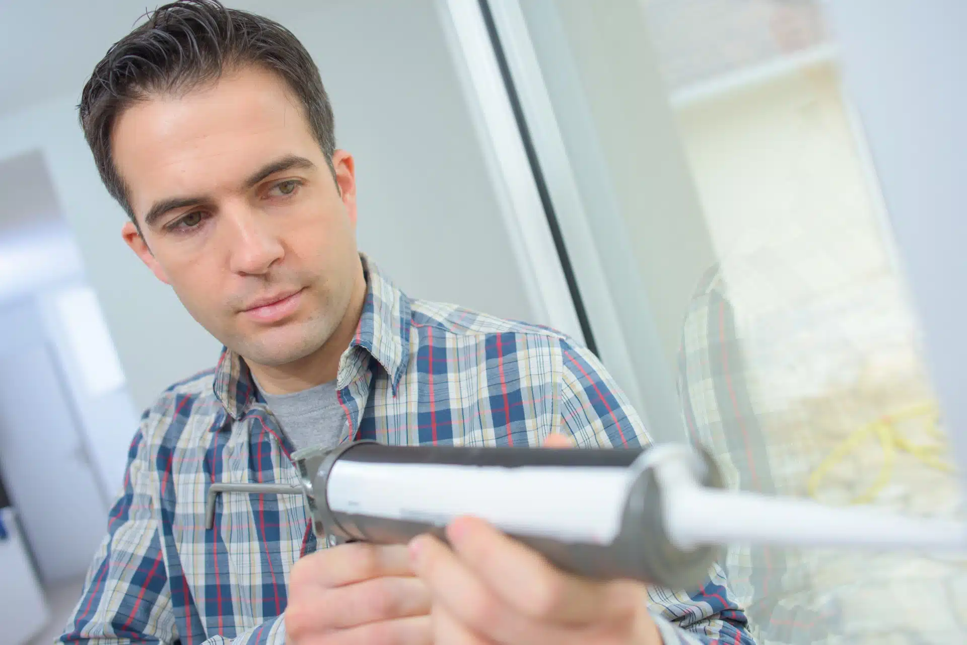 Man uses sealant gun on glass - dap clear sealant