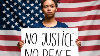 woman holding no justice no peace sign to seek racial justice