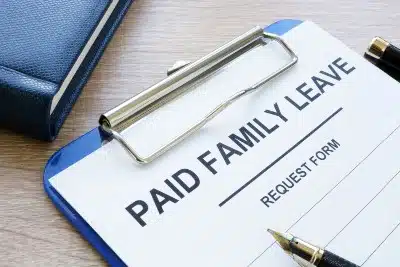 Paid Family Leave request form on blue clipboard with pen lying on top - Volvo plant