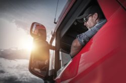 Male truck driver checks side mirror