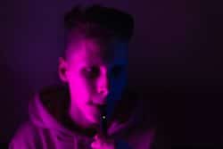 young teen male vaping under blacklight