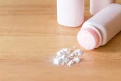 Bottle of powder on its side with some spilled onto wood table