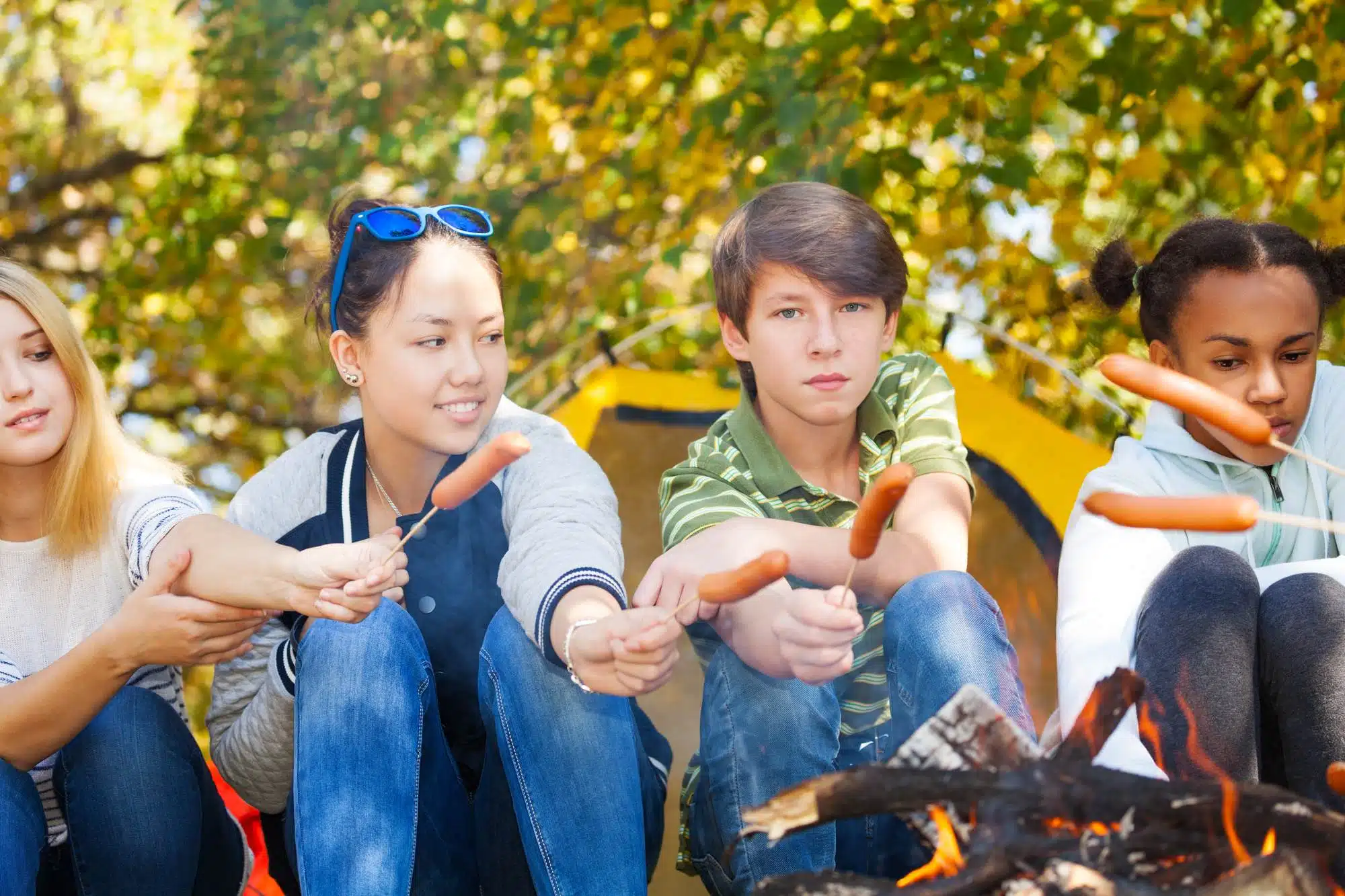 Camping teens cook hotdogs over a campfire. The Boy Scouts Youth Protection Training is designed to keep youth safe during every Scouting activity.