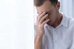 Depressed man with hand over his face and eyes closed