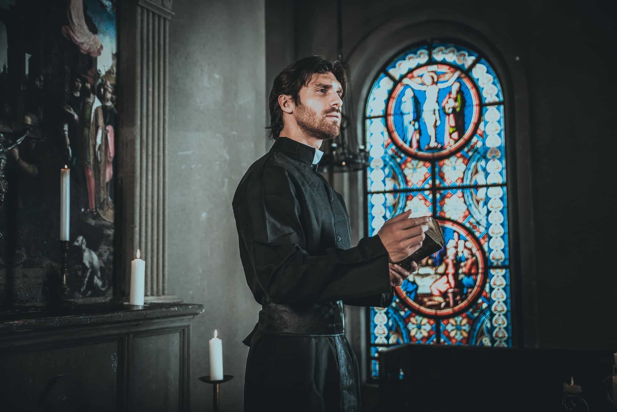 Priest holds open bible in church