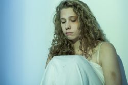 Sad and injured woman sits against a wall