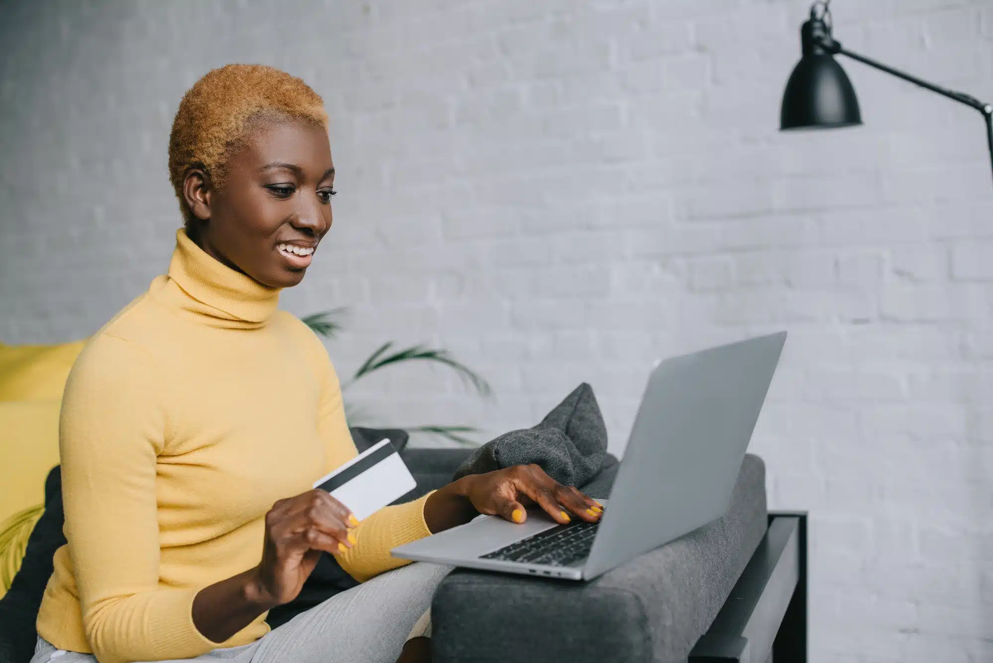 Woman holds prepaid debit card while on laptop