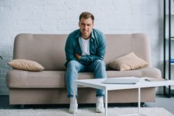 Man with abdominal pain sits on couch