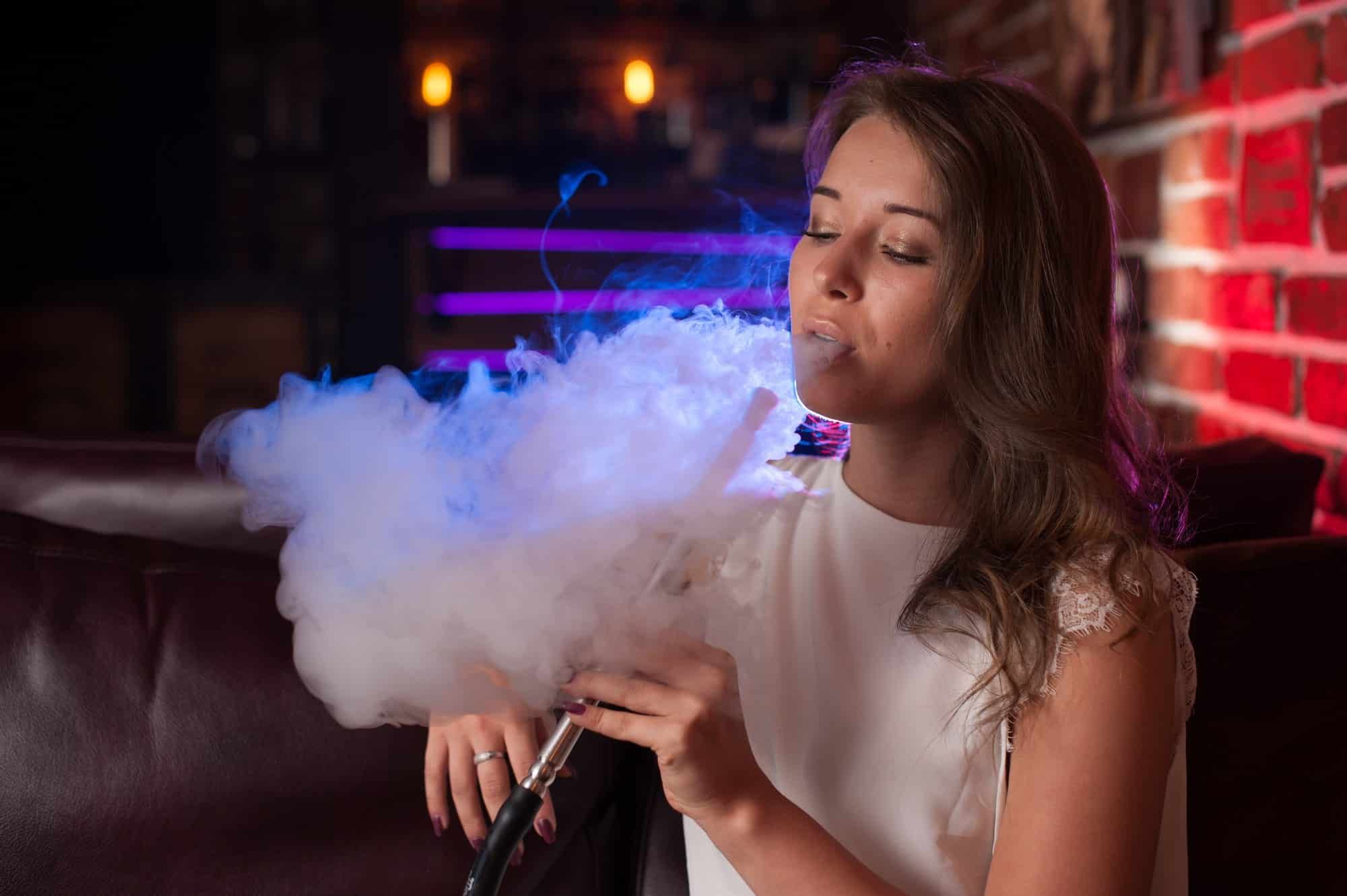 Young woman vaping at a bar