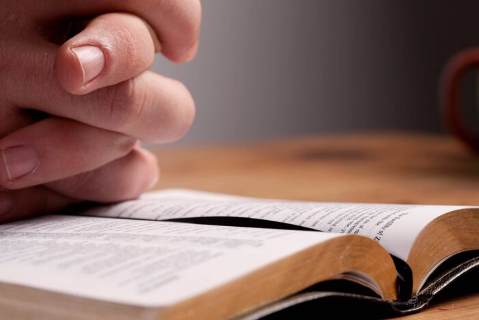 praying hands on top of bible