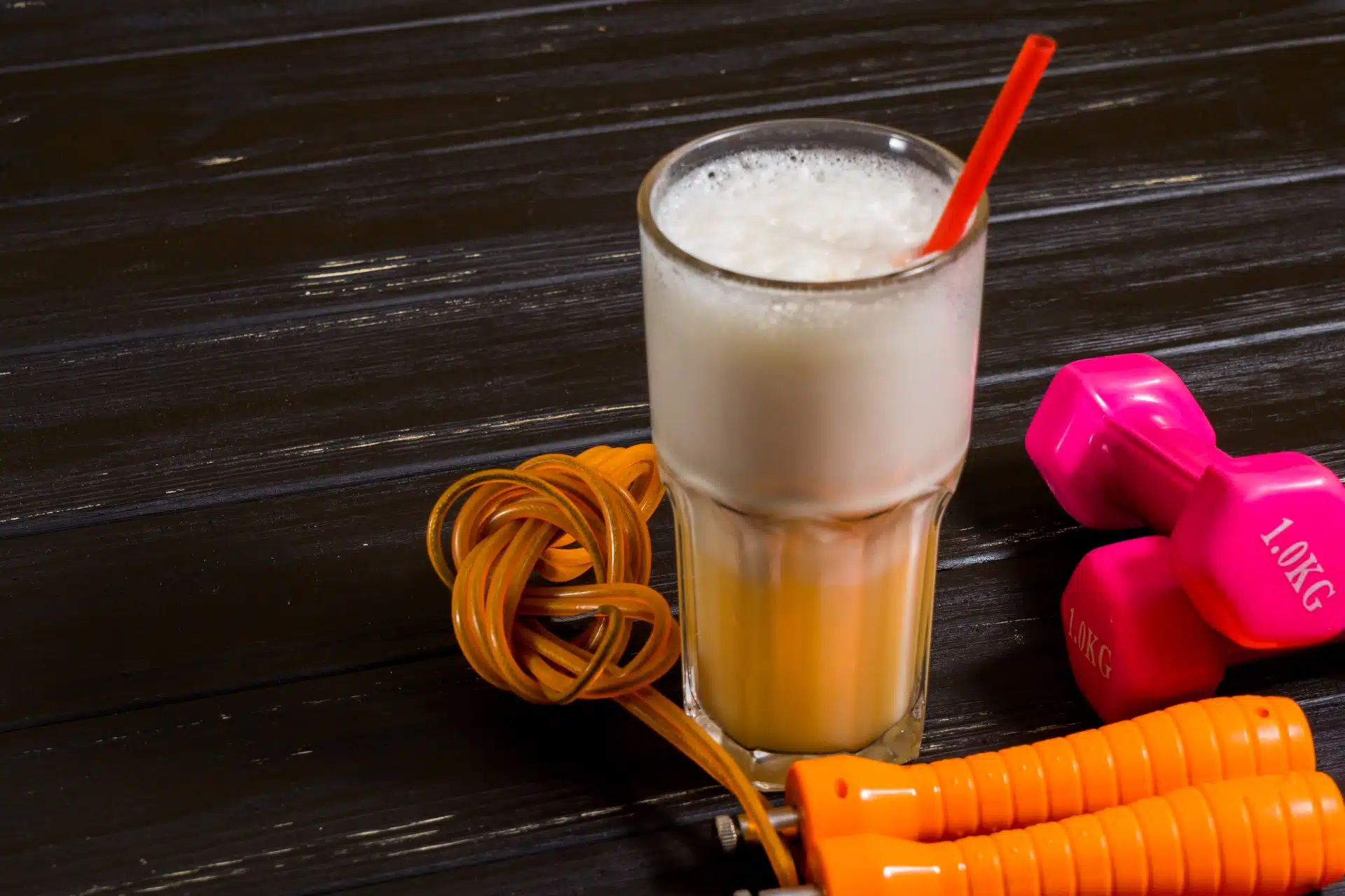A fitness shake in a glass next to hand weights and other exercise equipment - Core Power protein shake